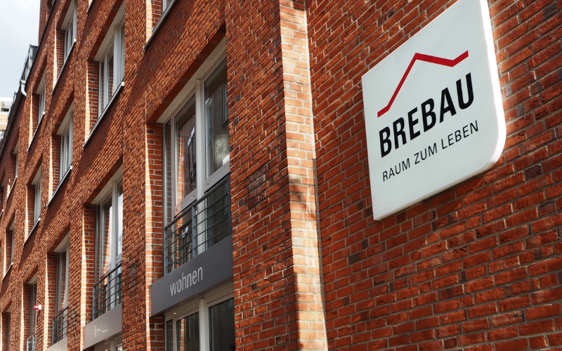 Zentrale 2 Backsteinhaus mit großen Brebau Logo an der Wand und vielen Fenstern.